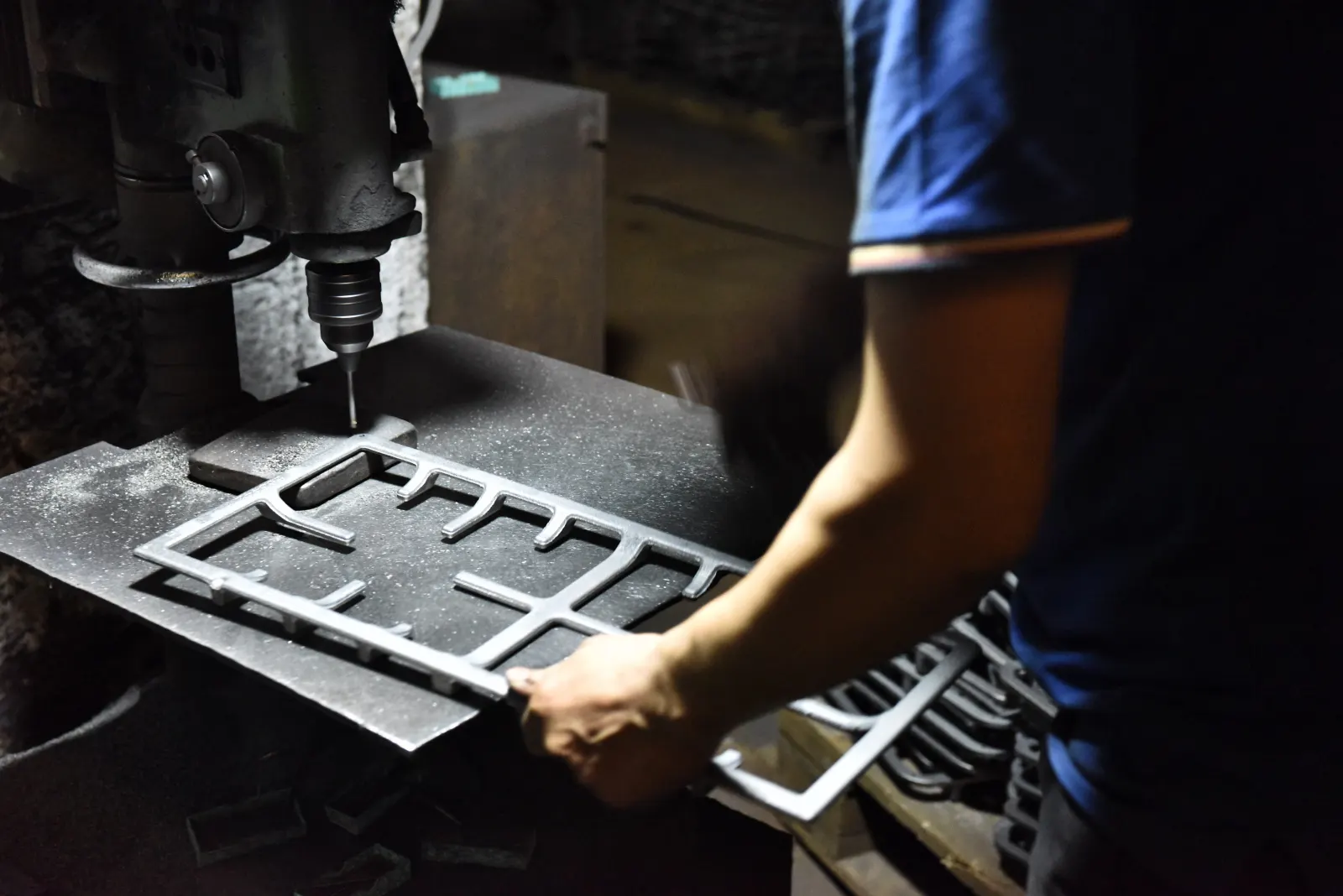 Operator machining or drilling a cast iron pan support part on production equipment